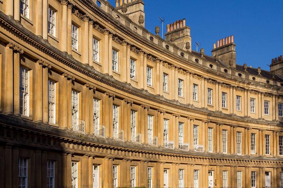 Curved Georgian facade of the Royal Crescent in Bath with identical columns and sash windows repeating along the terrace